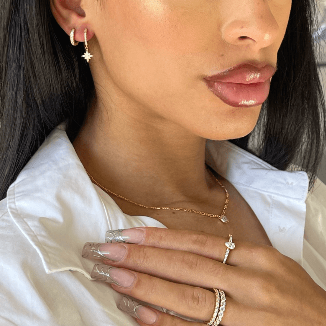 modal wearing stacking rings and small drop earrings. moon and star earrings