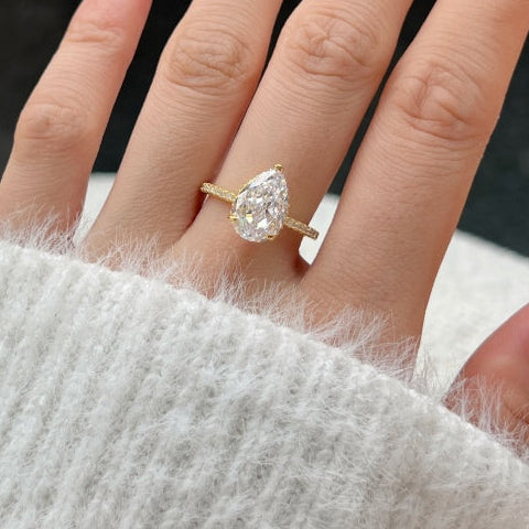 Hand wearing a pear-shaped diamond ring with