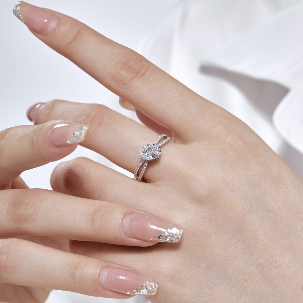 An oval-shaped ring with a main crushed-ice cubic zirconium stone, featuring a twisted double pavé band with smaller stones on a hand model.