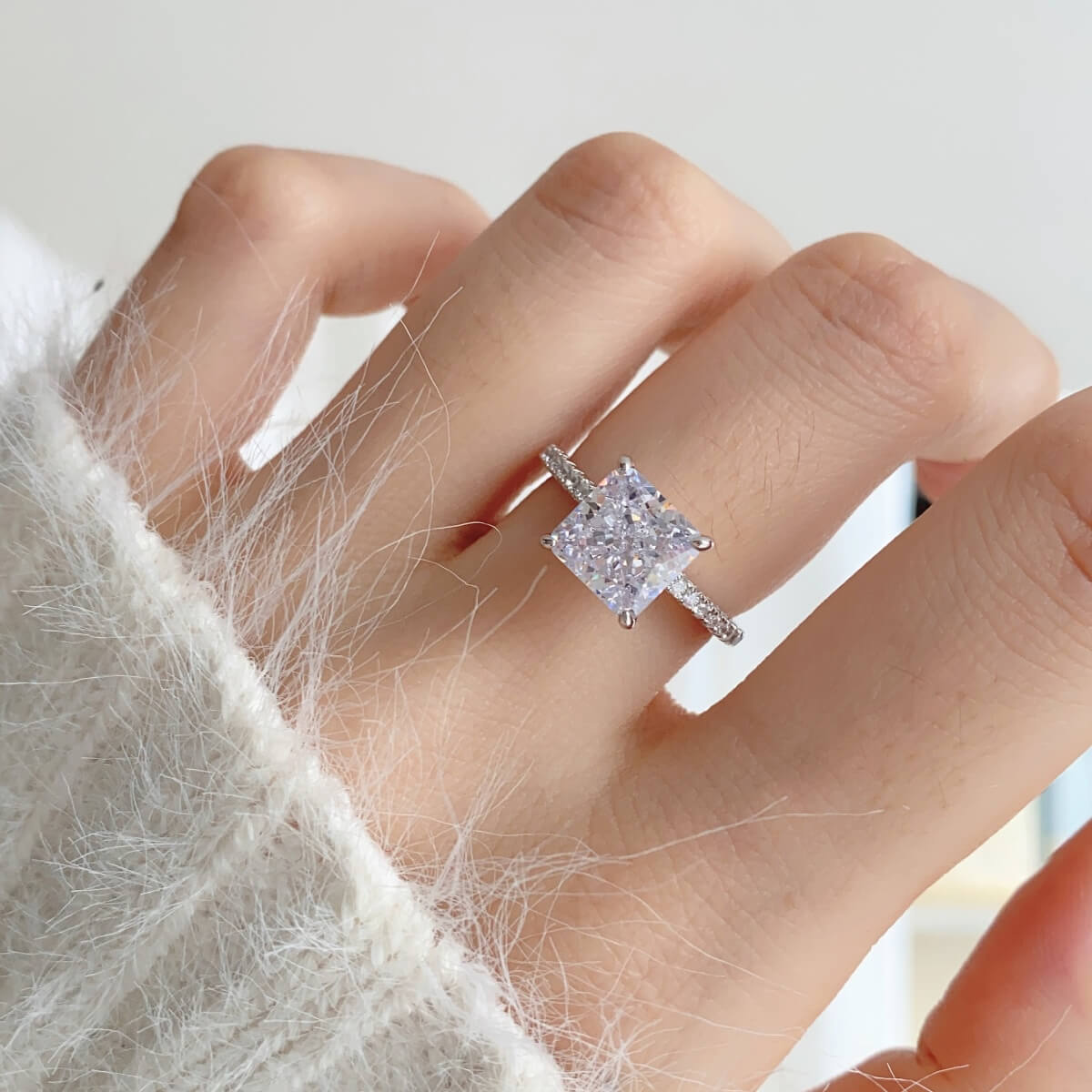 A close-up of a square-cut gemstone ring set in a polished 925 silver band. The ring features a clean, modern design with sharp edges and a simple yet elegant look, resting on a soft background
